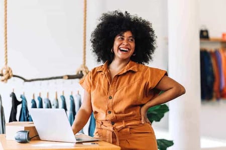 entrepreneurship in action as a woman stands in her small business selling denim jackets